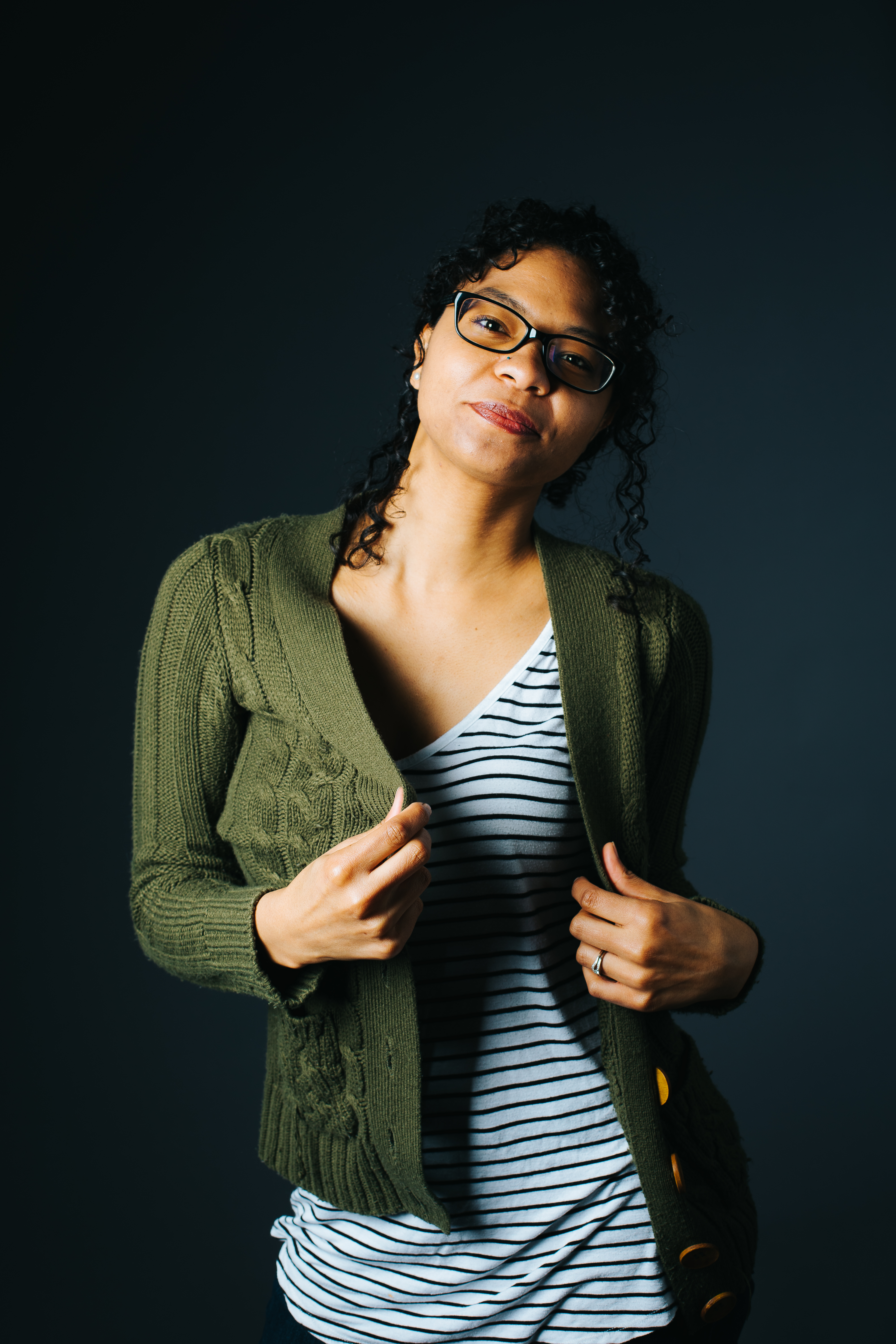 brown woman with black glasses wearing a green cardigan